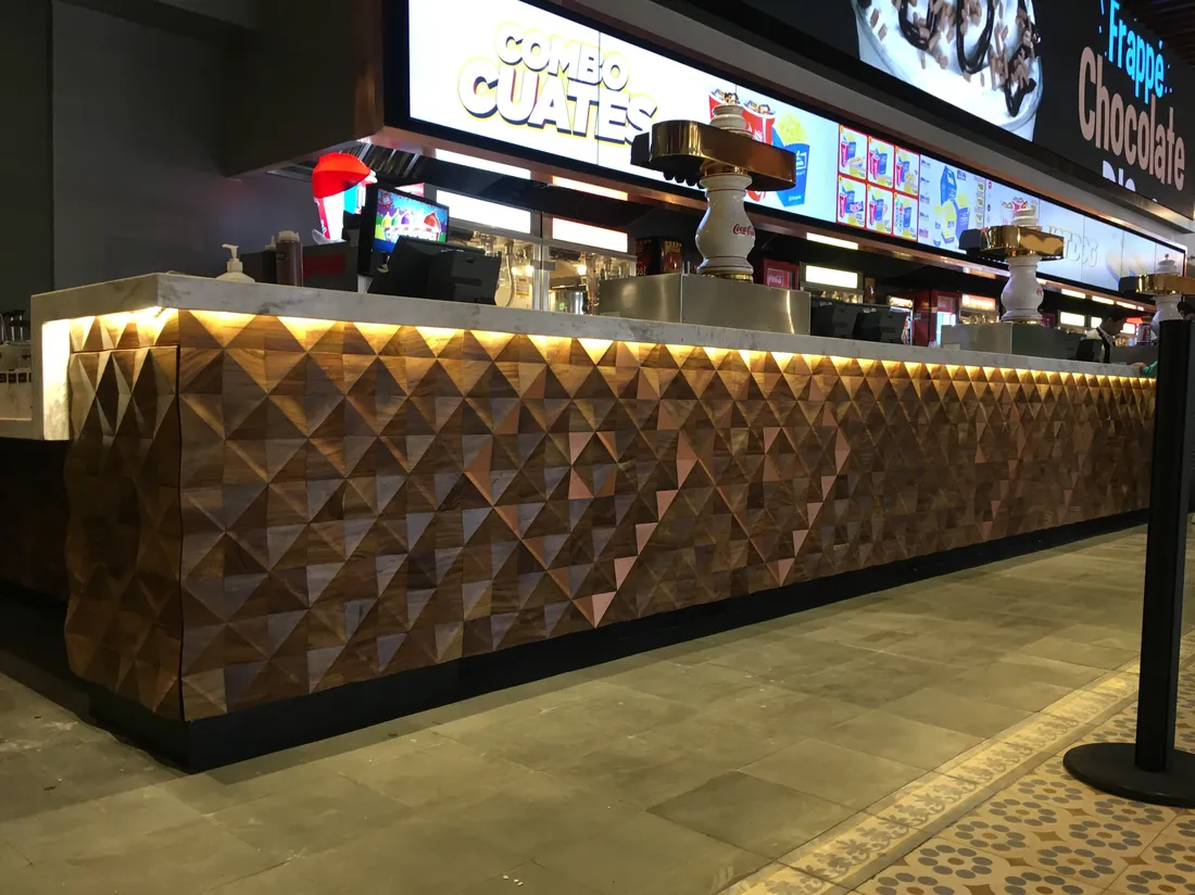 Barra de dulcería de cine con paneles de madera facetada e iluminación cálida integrada