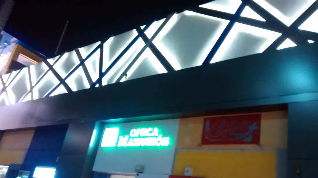 Friso iluminado de plaza comercial con letreros de locales