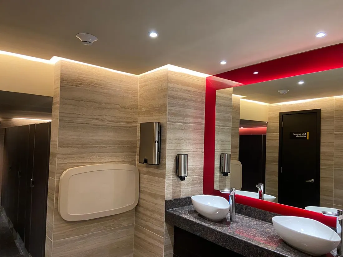 Sanitarios de cine con iluminación indirecta y acento en rojo