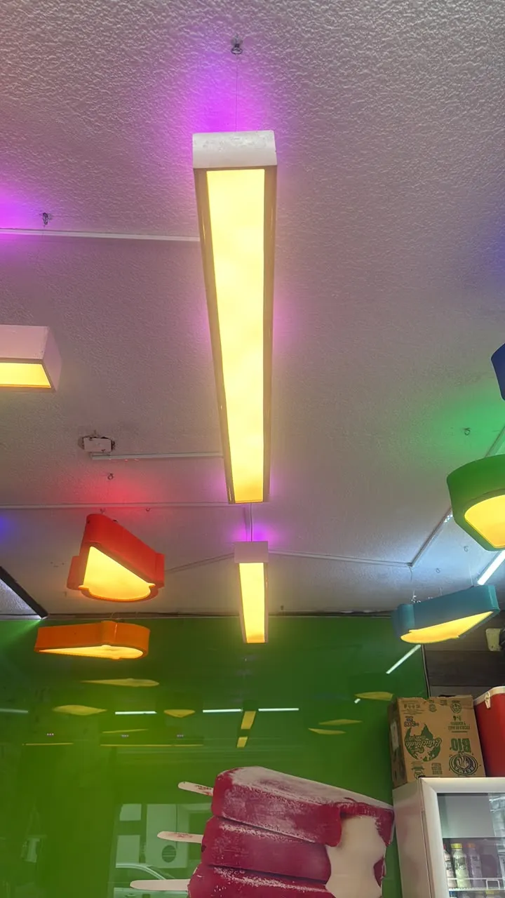 Luminarias colgantes de colores iluminando área de atención en local comercial