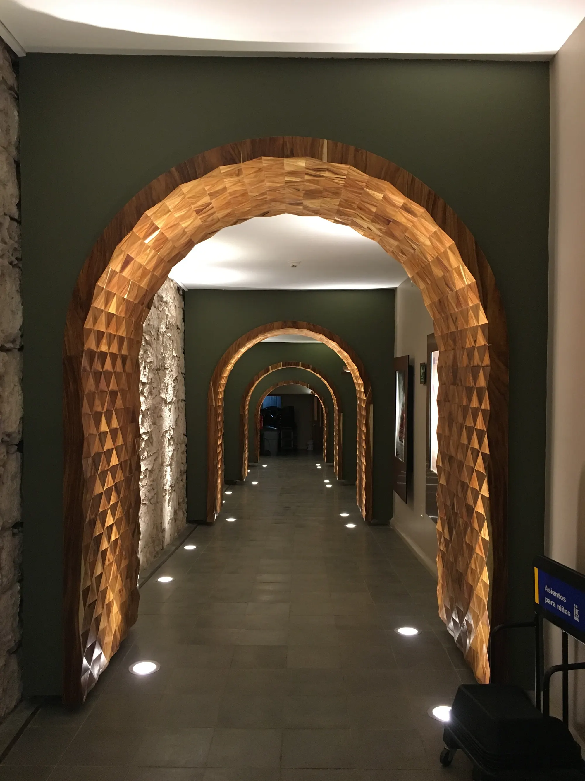 Corredor con arcos de madera e iluminación empotrada en piso
