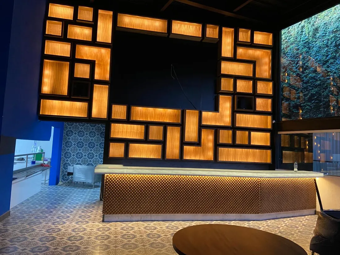 Muro de nichos de madera en composición tipo mosaico con iluminación cálida