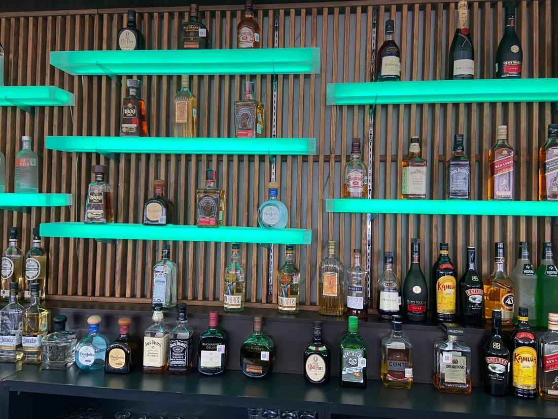 Repisas de vidrio con iluminación LED en verde para exhibir botellas premium