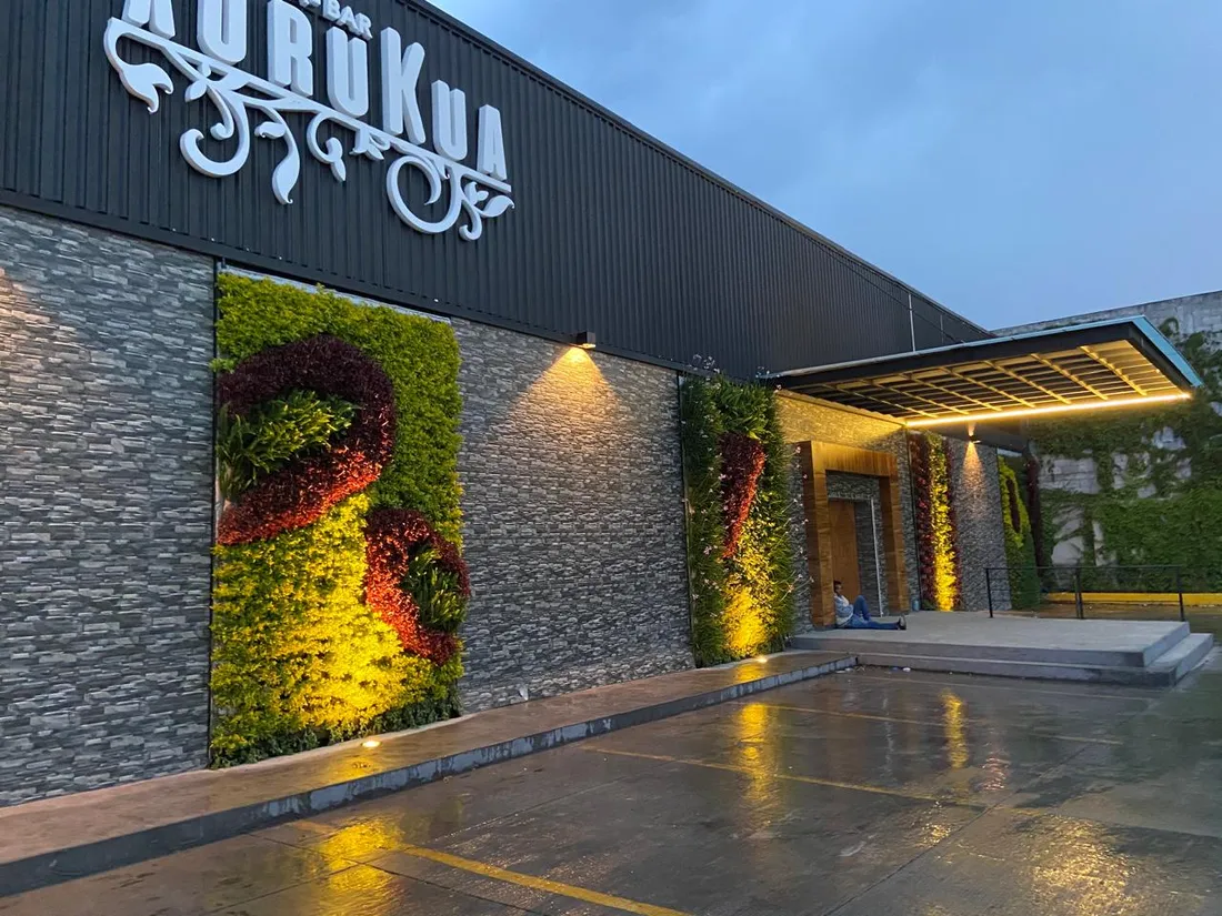 Fachada de bar con jardines verticales iluminados con proyectores